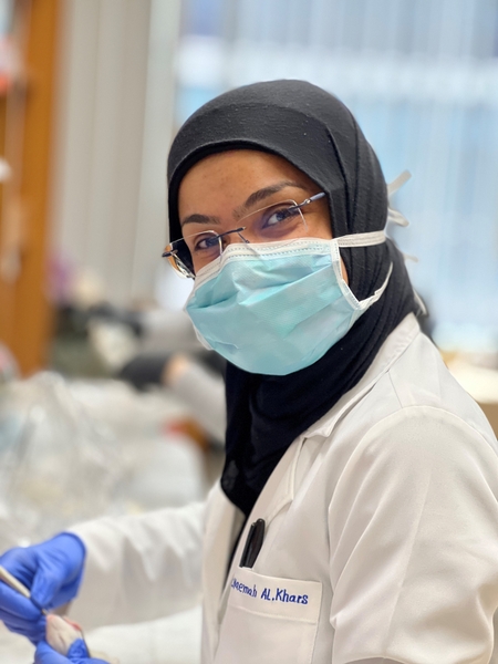 A portrait of Dr. Naemah Alkhars, wearing a lab coat and mask.