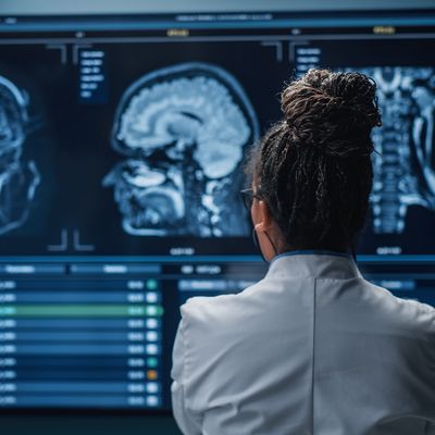 Medical Hospital Research Lab: Black Female Neuroscientist Looking at TV Screen, Analyzing Brain Scan MRI Images, Finding Treatment for Patient. Health Care Neurologist Curing People. Back View Zoom