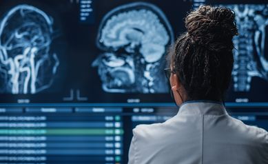 Medical Hospital Research Lab: Black Female Neuroscientist Looking at TV Screen, Analyzing Brain Scan MRI Images, Finding Treatment for Patient. Health Care Neurologist Curing People. Back View Zoom