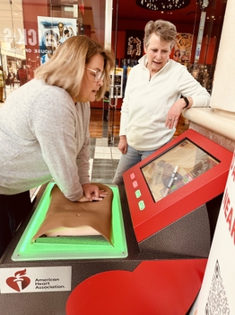 A woman is practicing CPR technique on new training technology.  She is learning how hard and deep to perform compressions to save a life. 