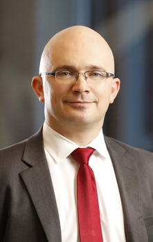 A young, bald man wearing a brown suit