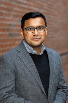 Headshot of Archan Ganguly, he is wearing dark rimmed glasses, neatly combed short dark hair, a blazer over a button up shirt with a slight smile.