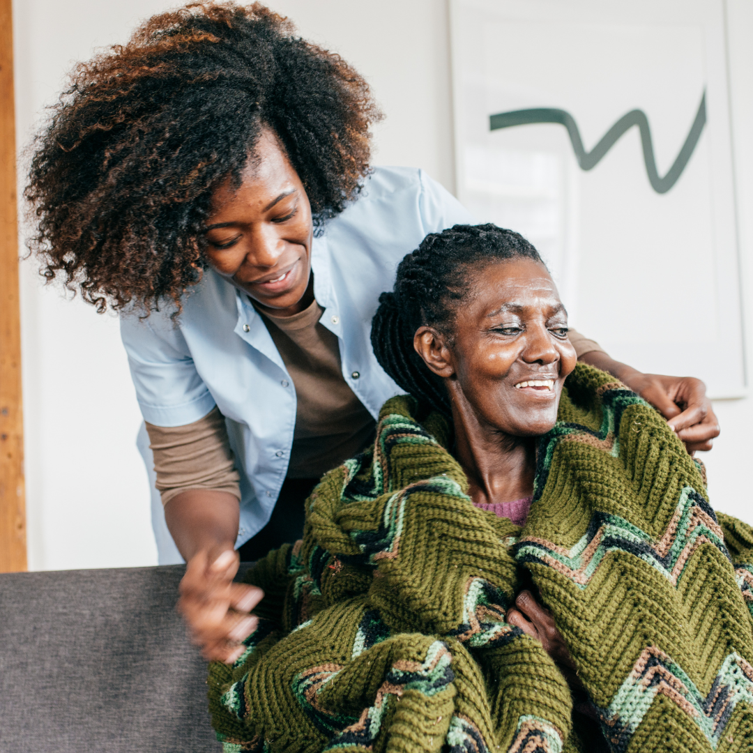 Young woman holds shoulders of older woman wrapped in blanket.