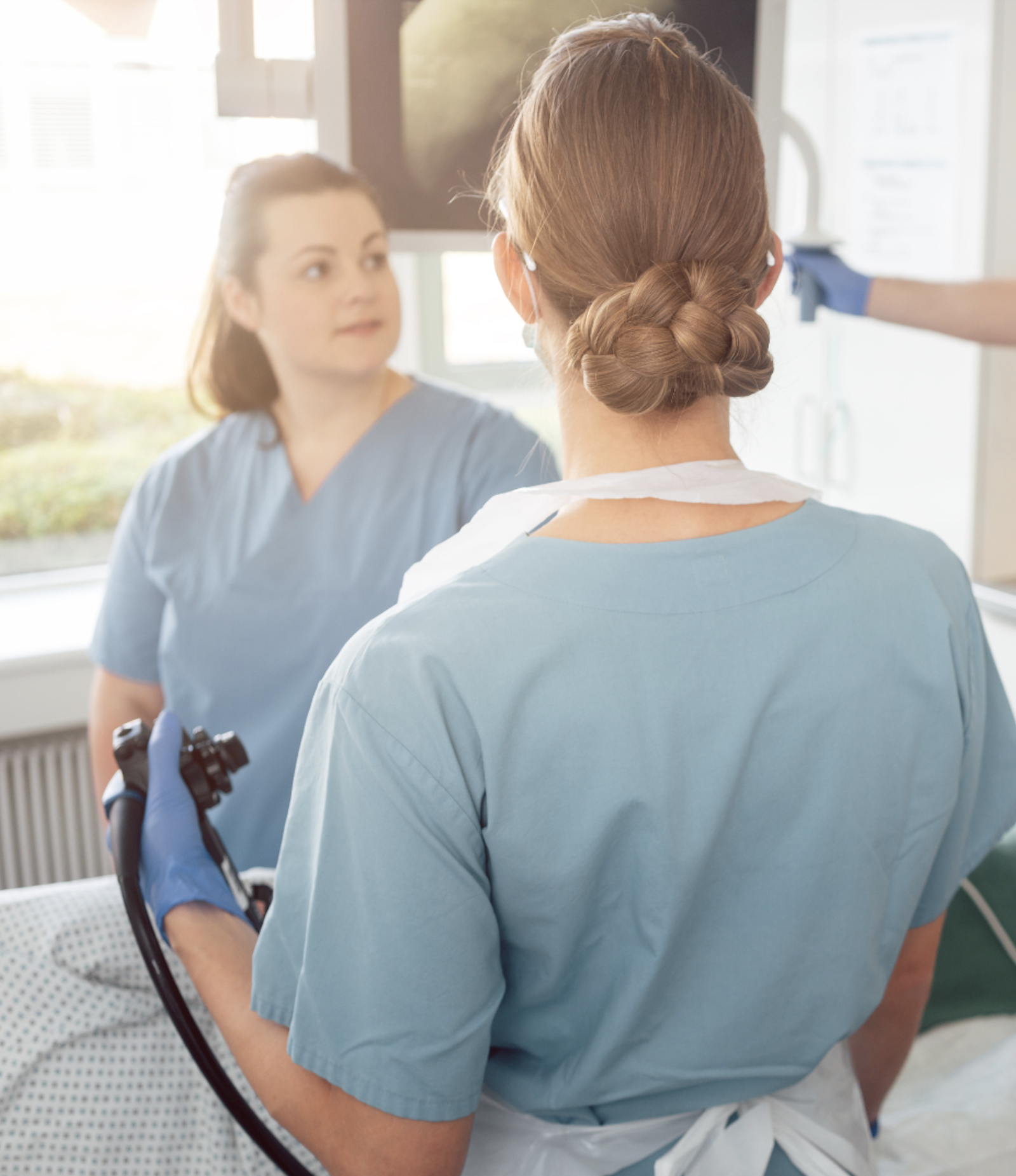Two medical professionals perform an endoscopy on patient.