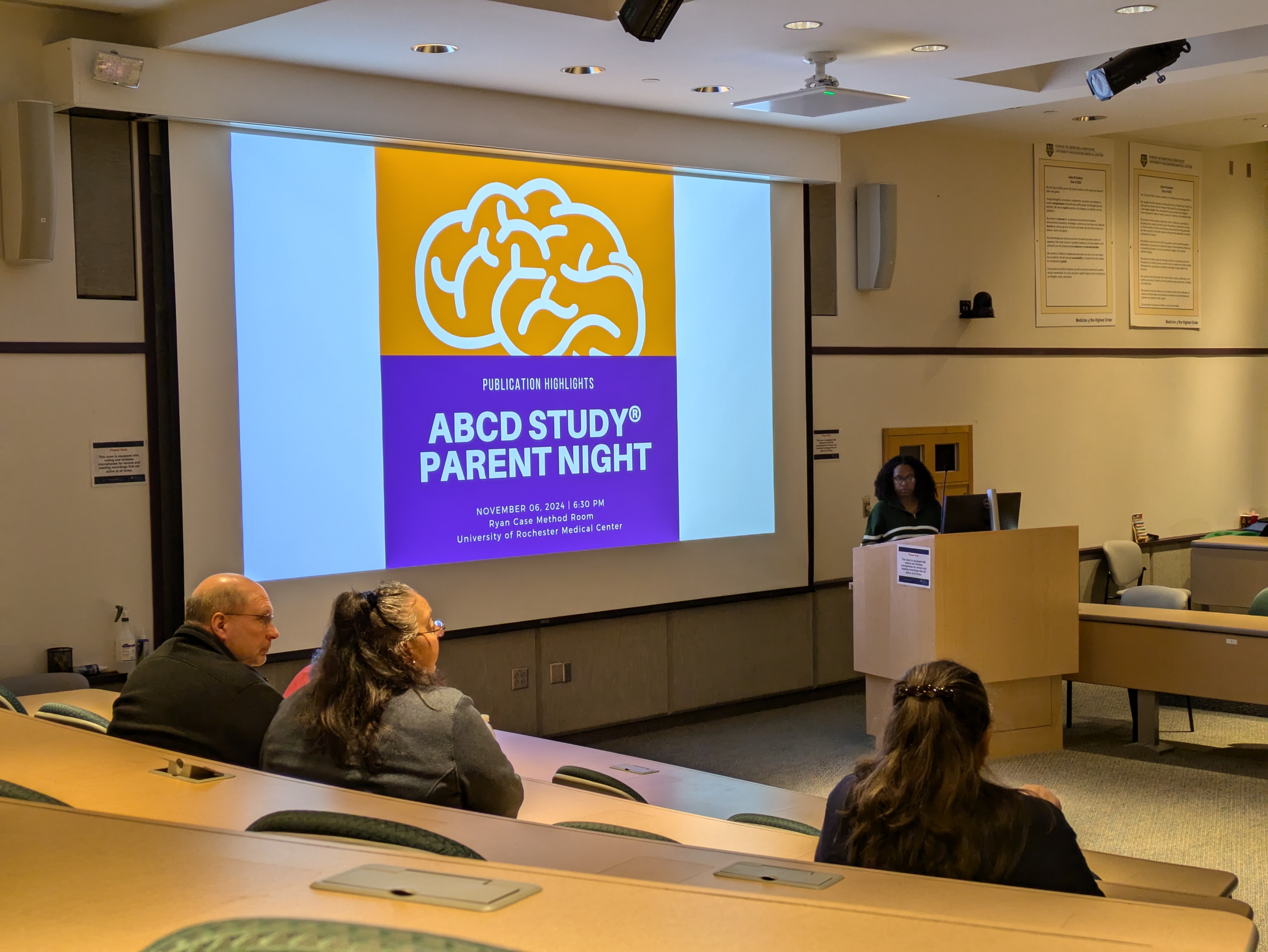 Lecture hall with people looking at screen that says Parent's Night ABCD Study