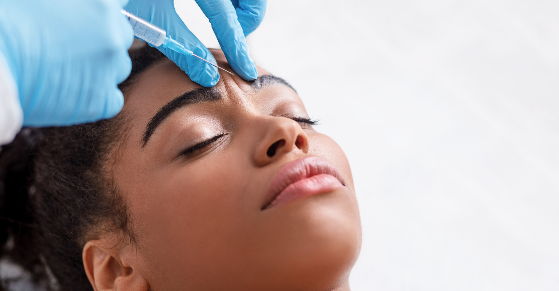 Woman receives botox injection between eyebrows.