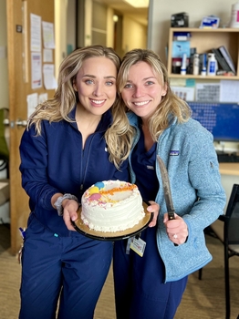 Two women holding a cake that says "Congratulations!"