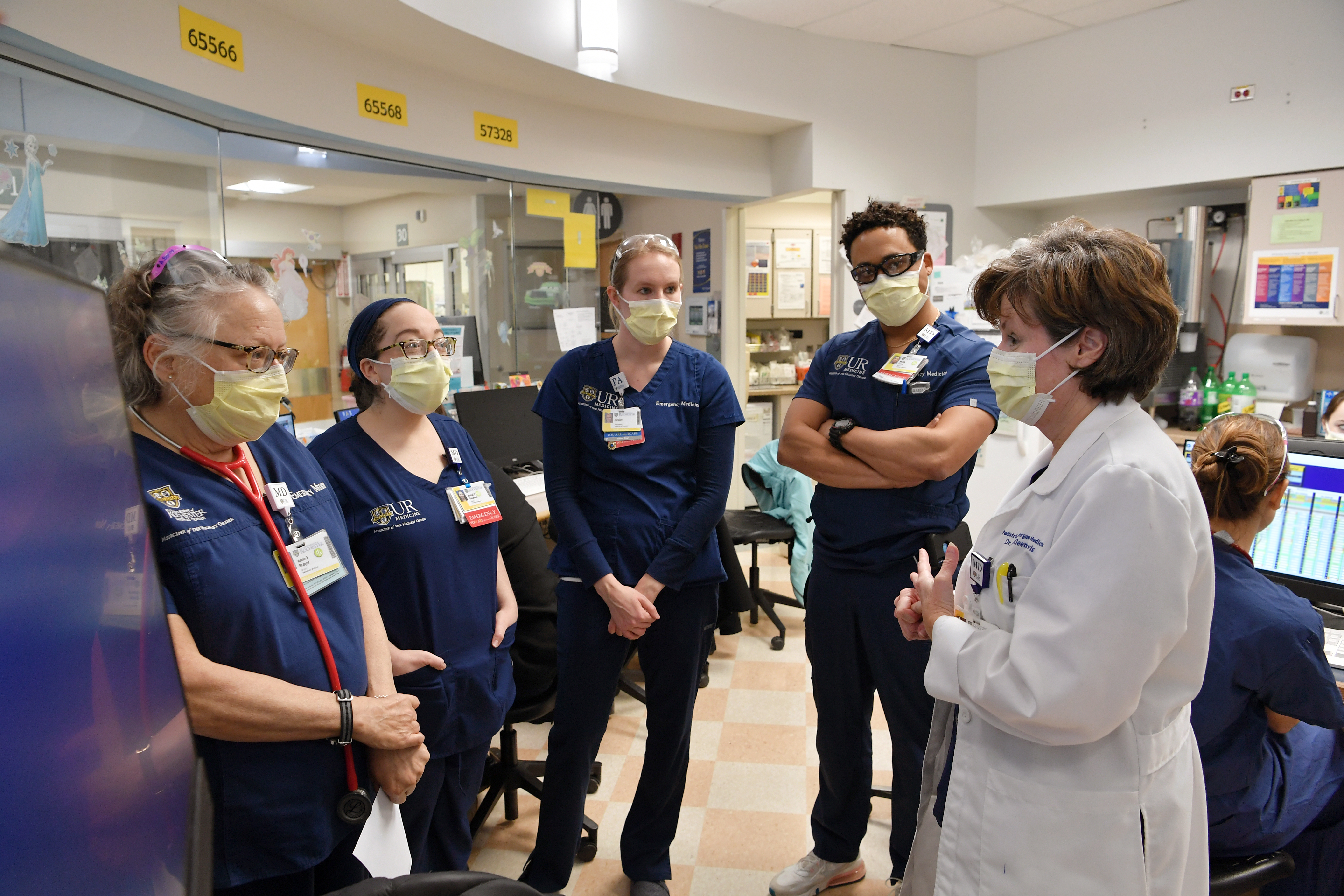 Four URMC employees stand and listen to a physician in the hospital.