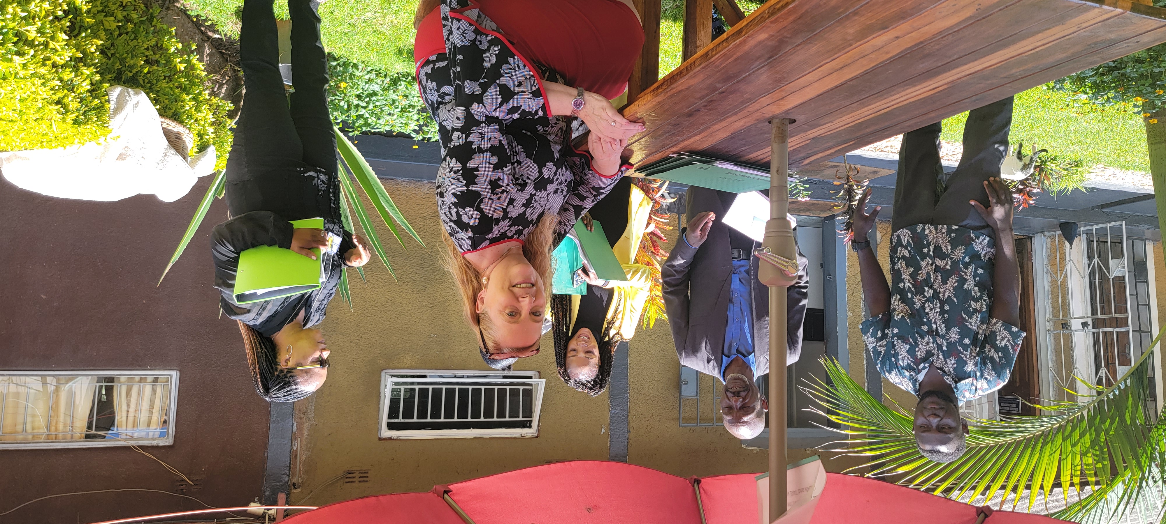 Group of people sit around a table outdoors, working with Gretchen L. Birbeck, MD, MPH.