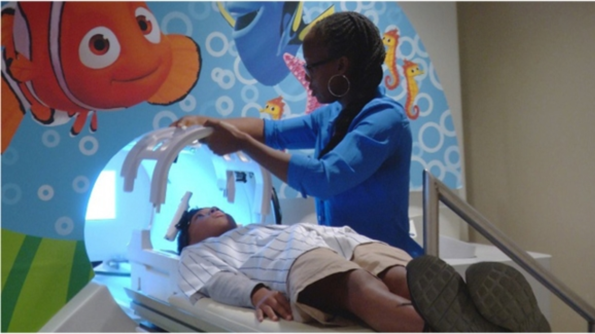 Child receiving a brain scan while health care provider helps.