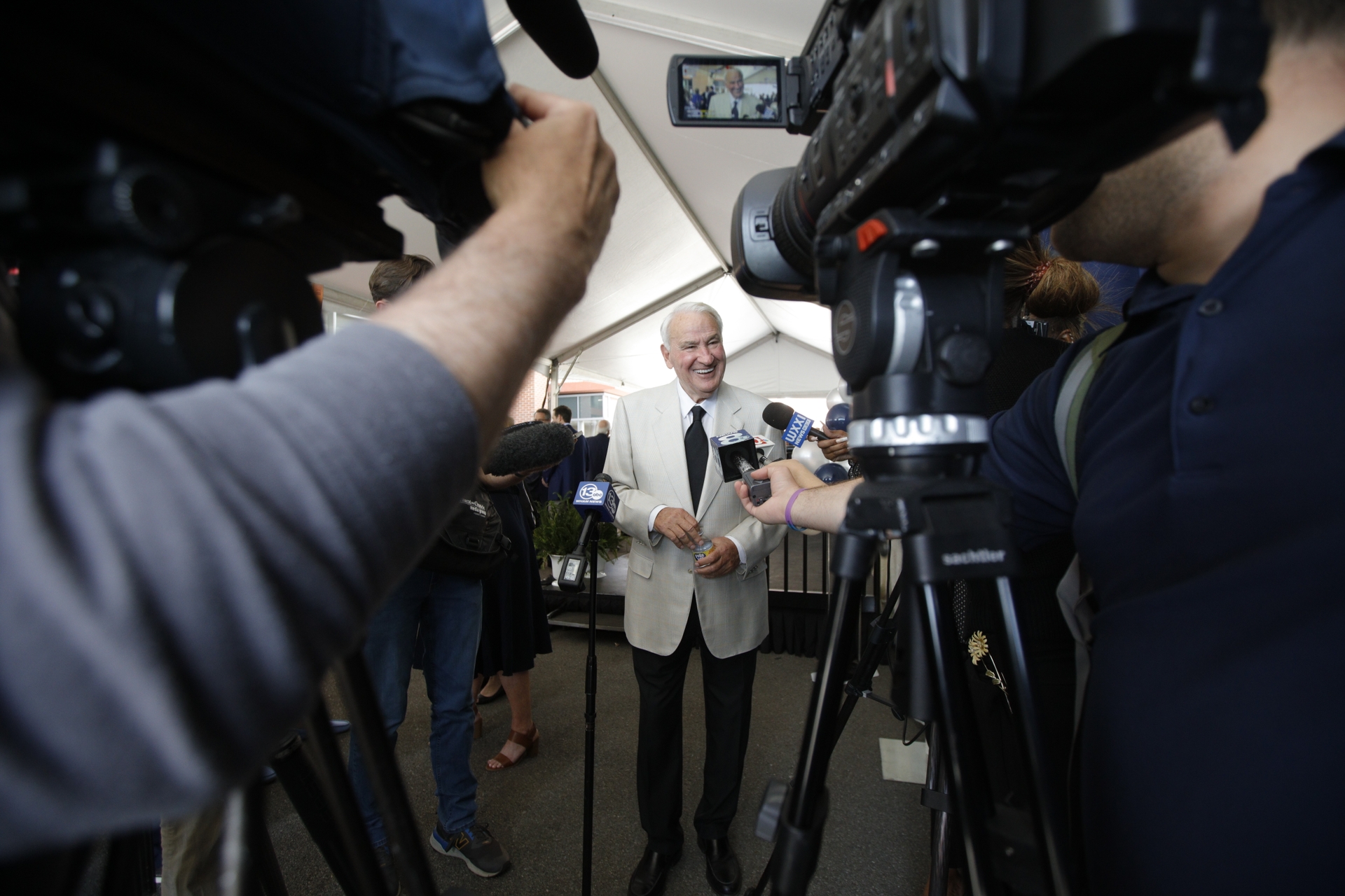 Tom Golisano surrounded by cameras and microphones during reporter gaggle.