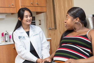 a doctor in a lab coat talking with pregnant patient