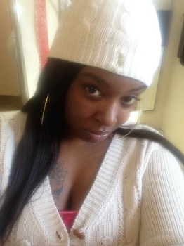 Young Black woman wearing a white sweater and knit cap.