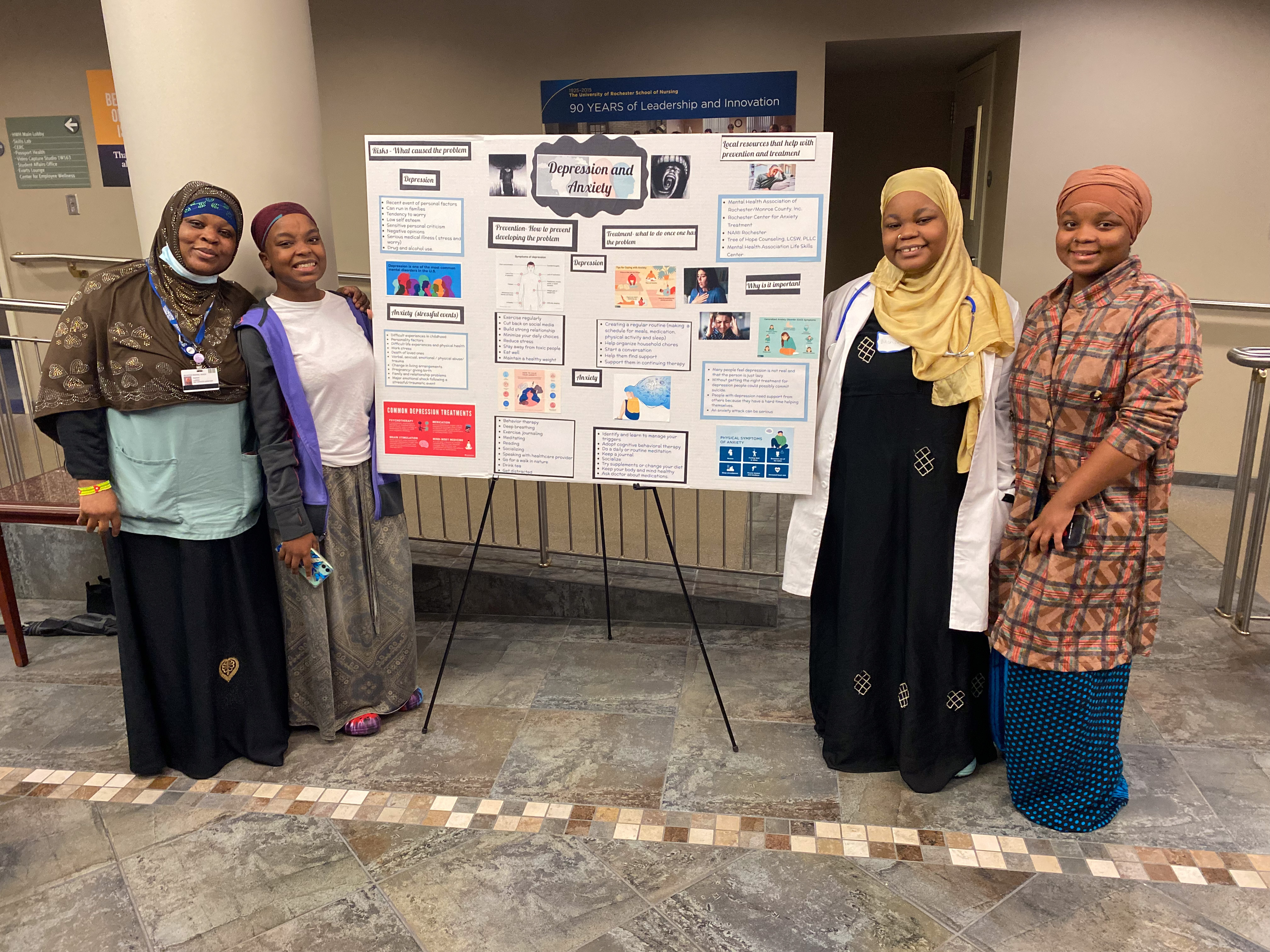 Four people posing in front of research poster.