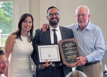 Dr. Assery stands between Dr. Tsigarida and Dr. Caton, holding two awards