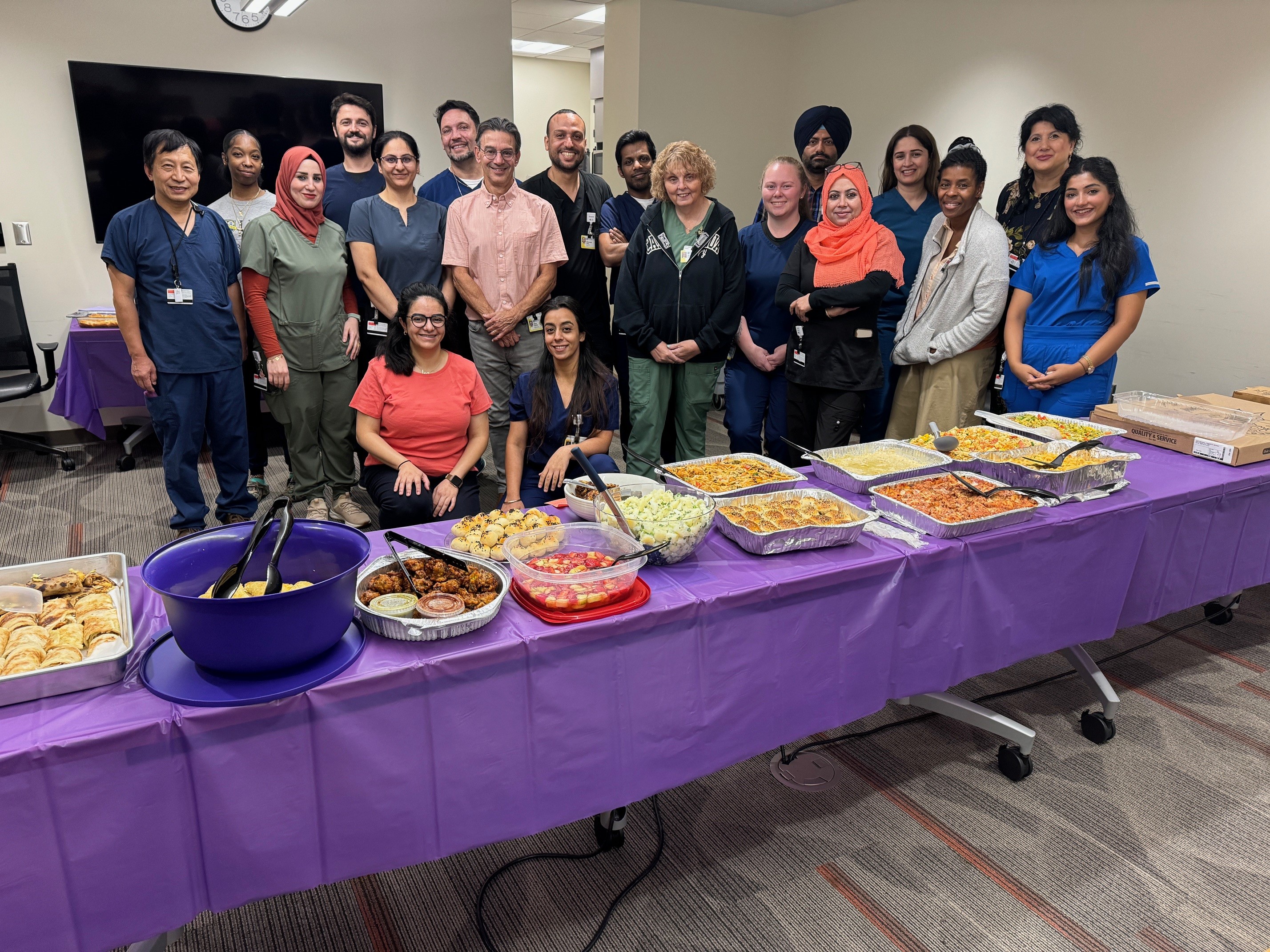 a group of people stand behind a long table covered with a wide variety of foods from different cultures