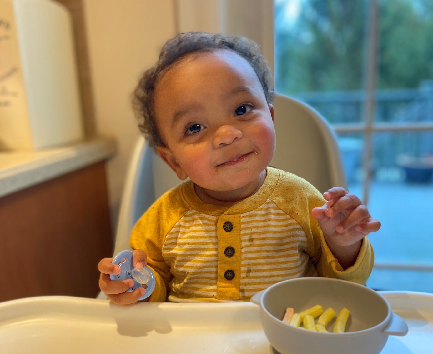 Toddler Noah Ludgood sits in a high chair and eats a snack.