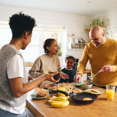 Family and boy with Down syndrome making pancakes for breakfast