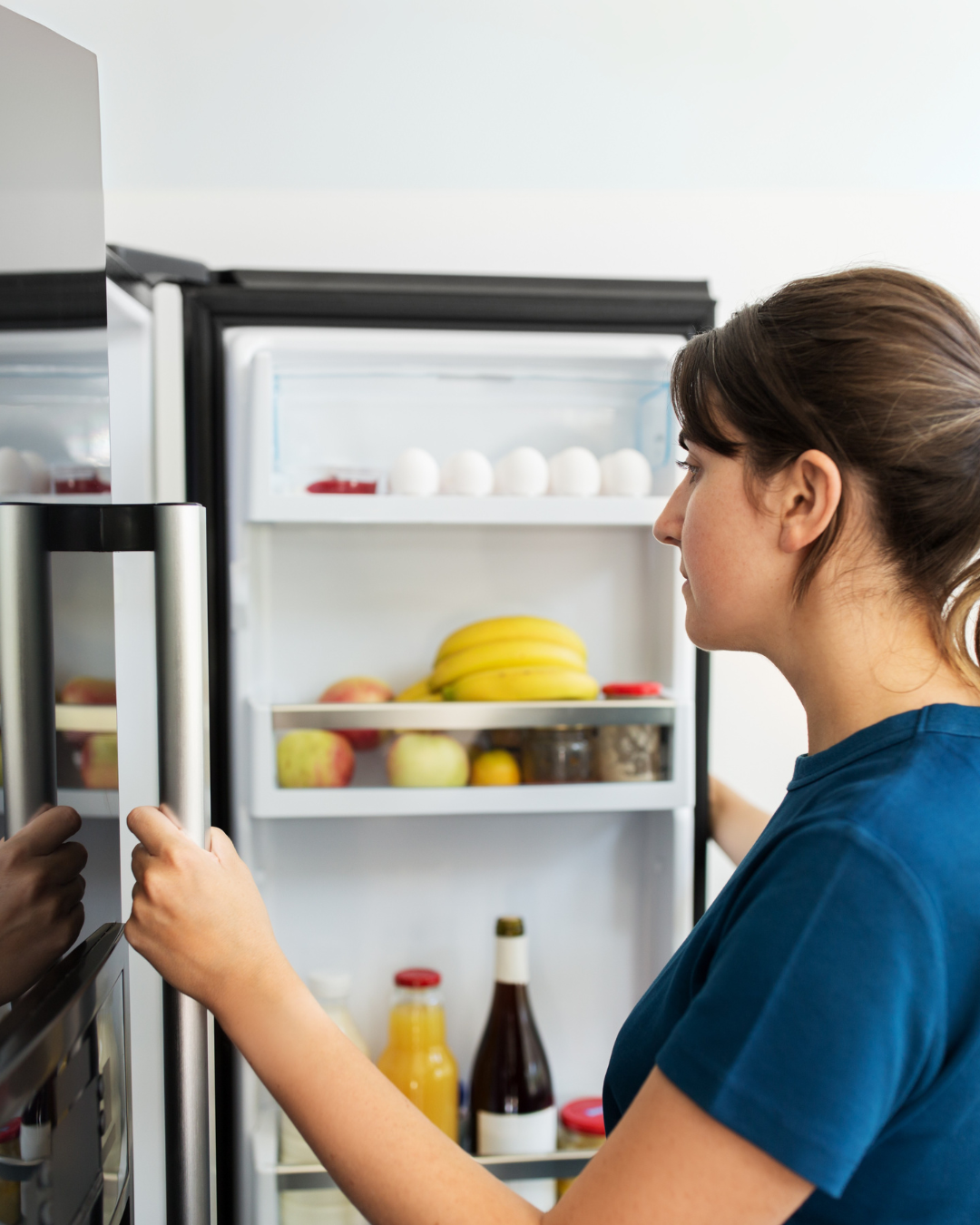 Woman looking in fridge deciding what to eat.