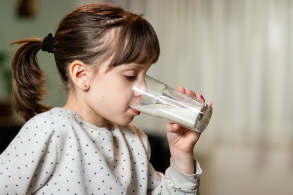 young girl with bangs drinking milk from glass