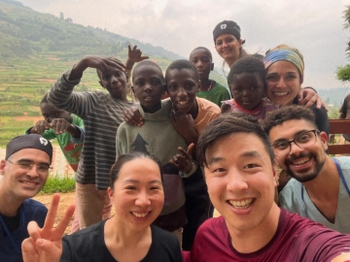A cluster of dental residents and Ugandan children, smiling and posing.