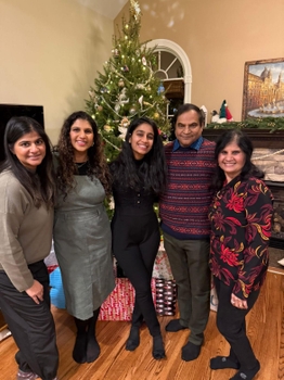 5 people pose together in front of a Christmas tree.