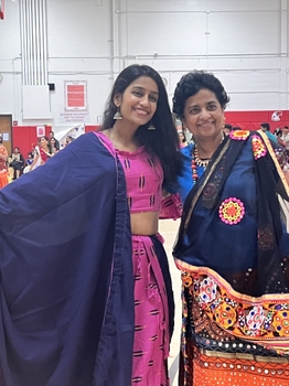 Two women stand together wearing traditional Indian saris.