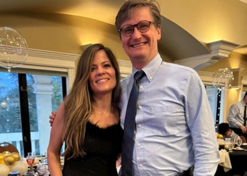 A man and a woman in formal attire stand together.