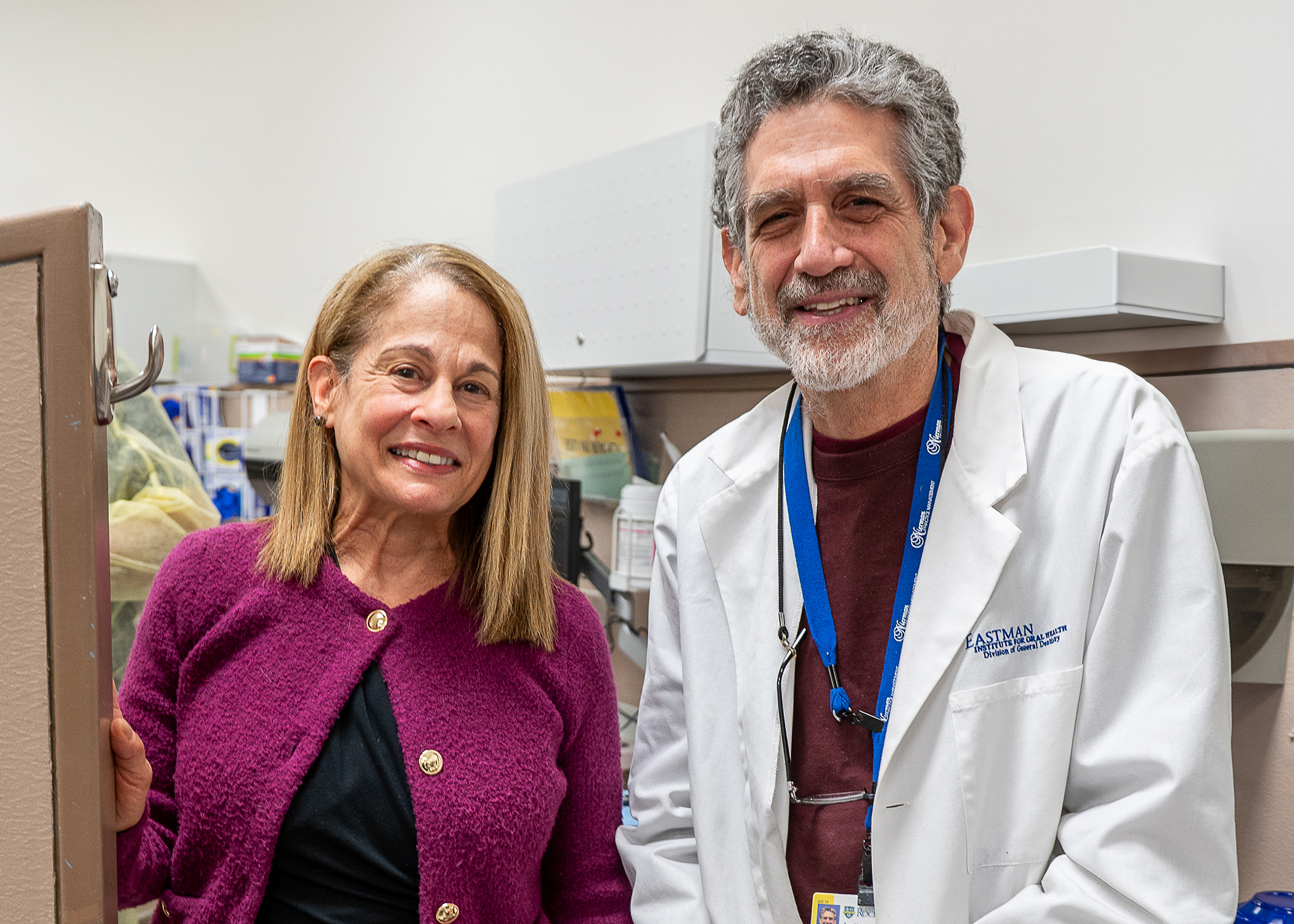 a man in a white lab coat smiles next to a woman in a dental clinic.