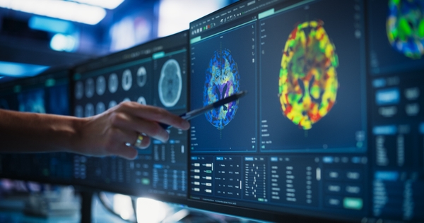 A medical researcher in a modern lab examines a CT scan on a computer screen.