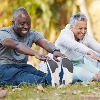 Fitness, stretching and senior people in park for healthy body, wellness and active workout outdoors. Retirement, sports and men and women stretch legs on grass for exercise, training and warm up