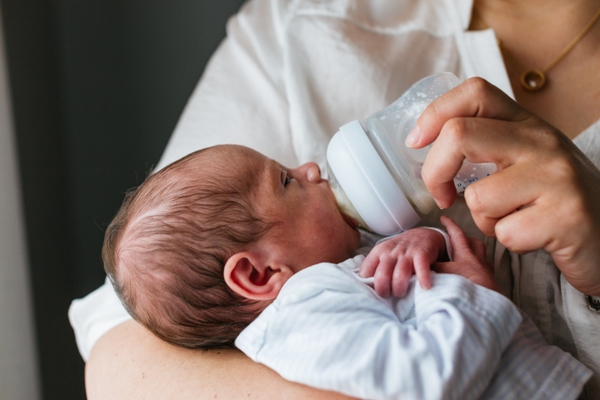 newborn baby bottle feeding in mom's arms