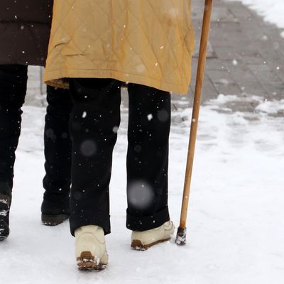 Person walking with a cane through the snow
