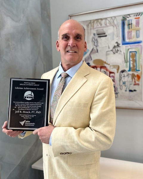 Man in a white and blue suit holding an award