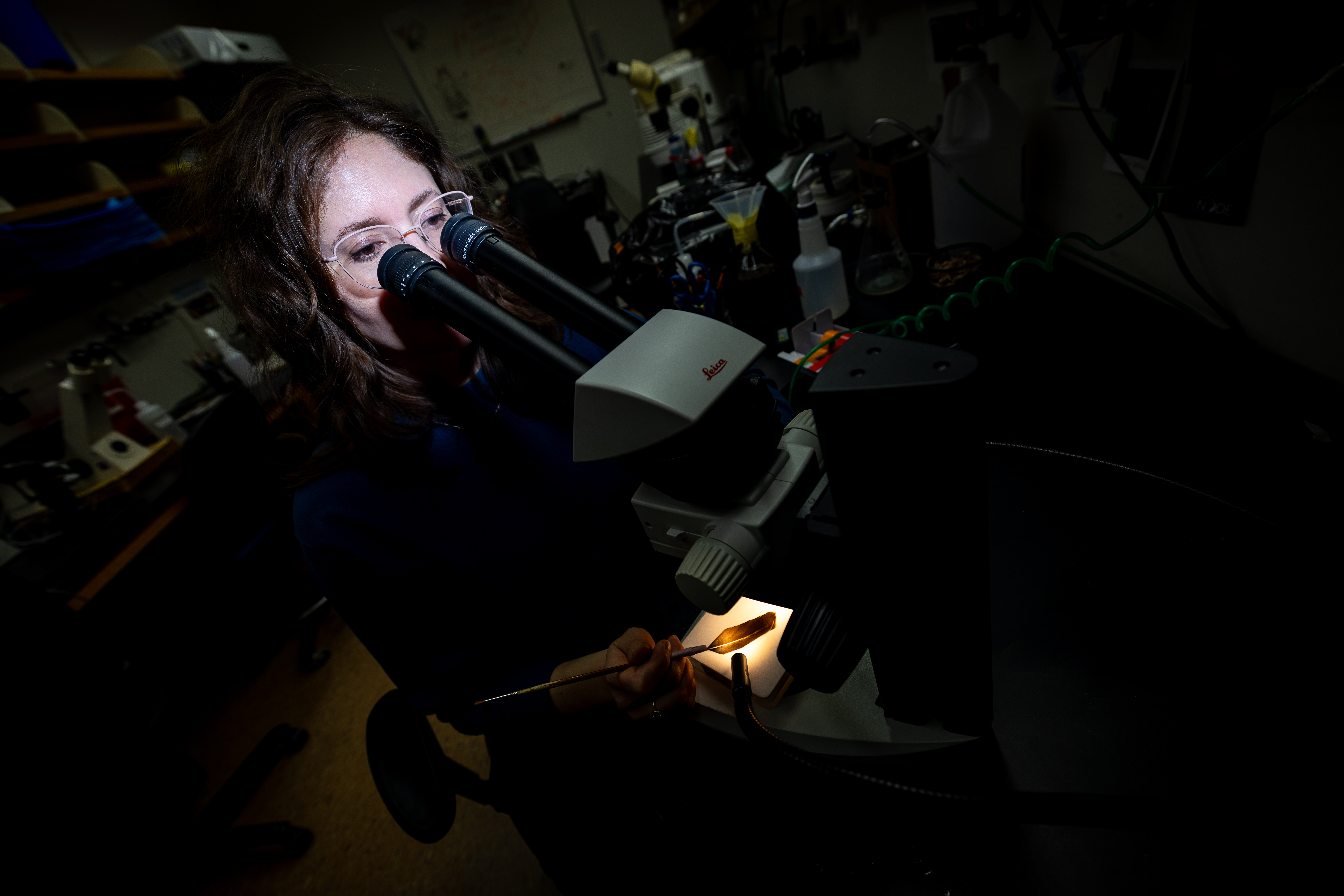 A woman facing a microscope in a laboratory
