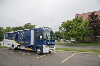 A smilemobile parked next to a school.
