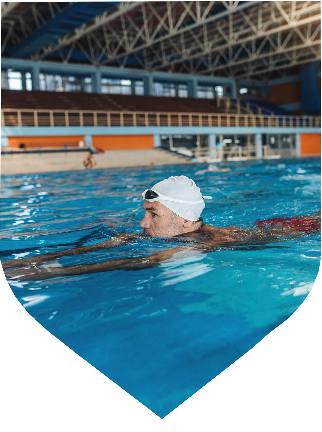 Man swims in pool lane with swim cap and goggles.