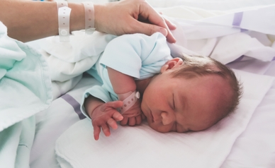 newborn baby in hospital with mom hand touching the child