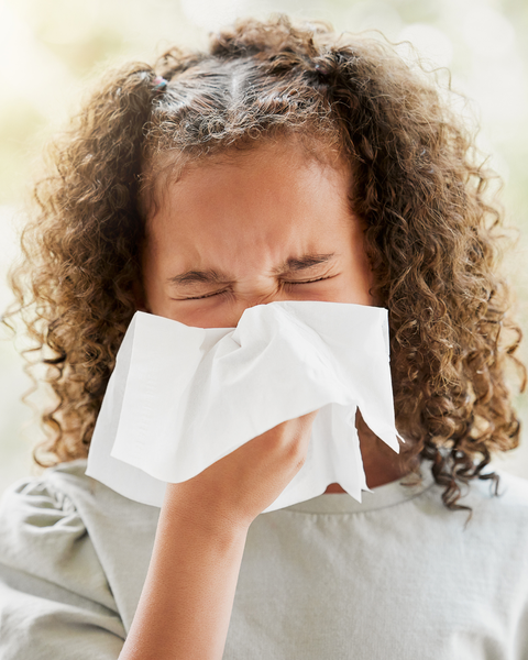 young african american girl blowing her nose with a tissue outside
