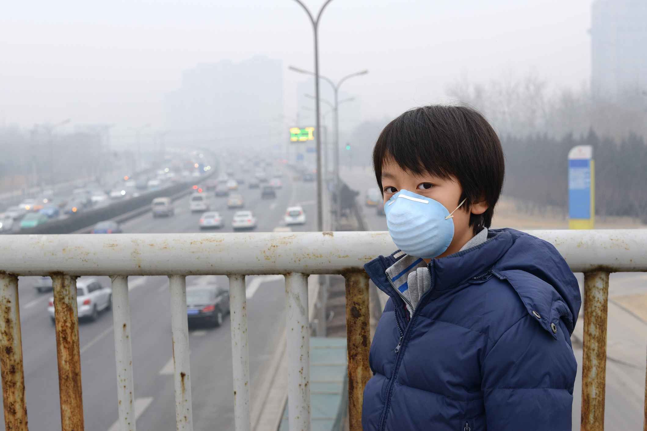 Child wearing a mask overlooking a highway in Bejing