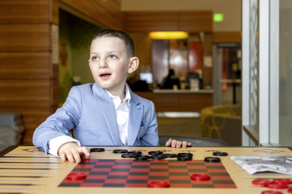 young boy sitting at a checkers table