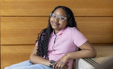 young girl in pink shirt sitting, smiling at camera