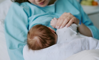 young baby facing away from camera, breastfeeding under slightly lifted shirt