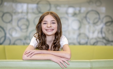 young girl in white dress sitting on green couch