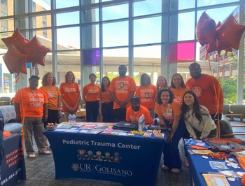 A group of people wearing orange shirts advocating to end gun violence stand together at a tabling event