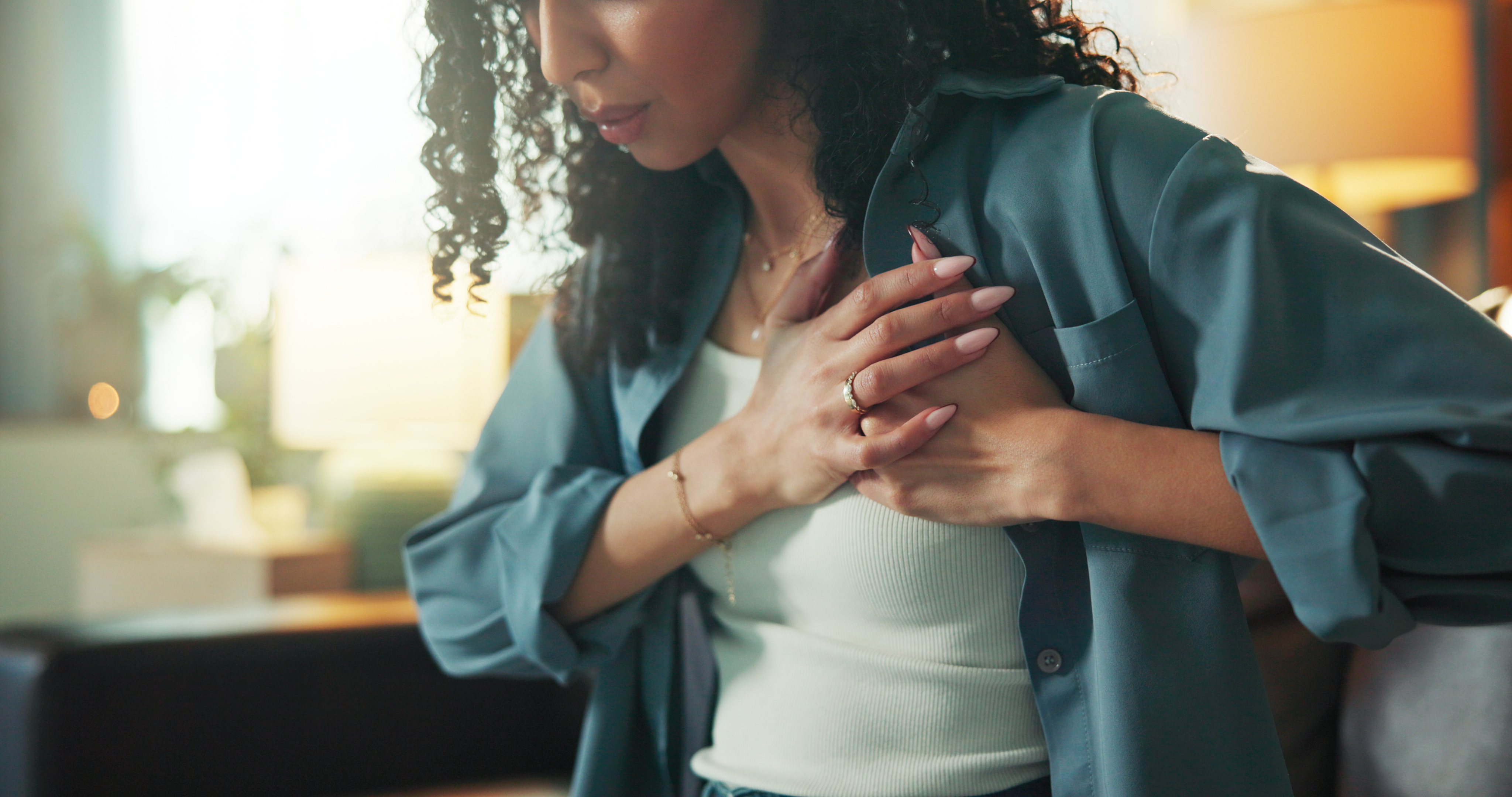 A woman in a white shirt and blue jacket holds her chest in pain