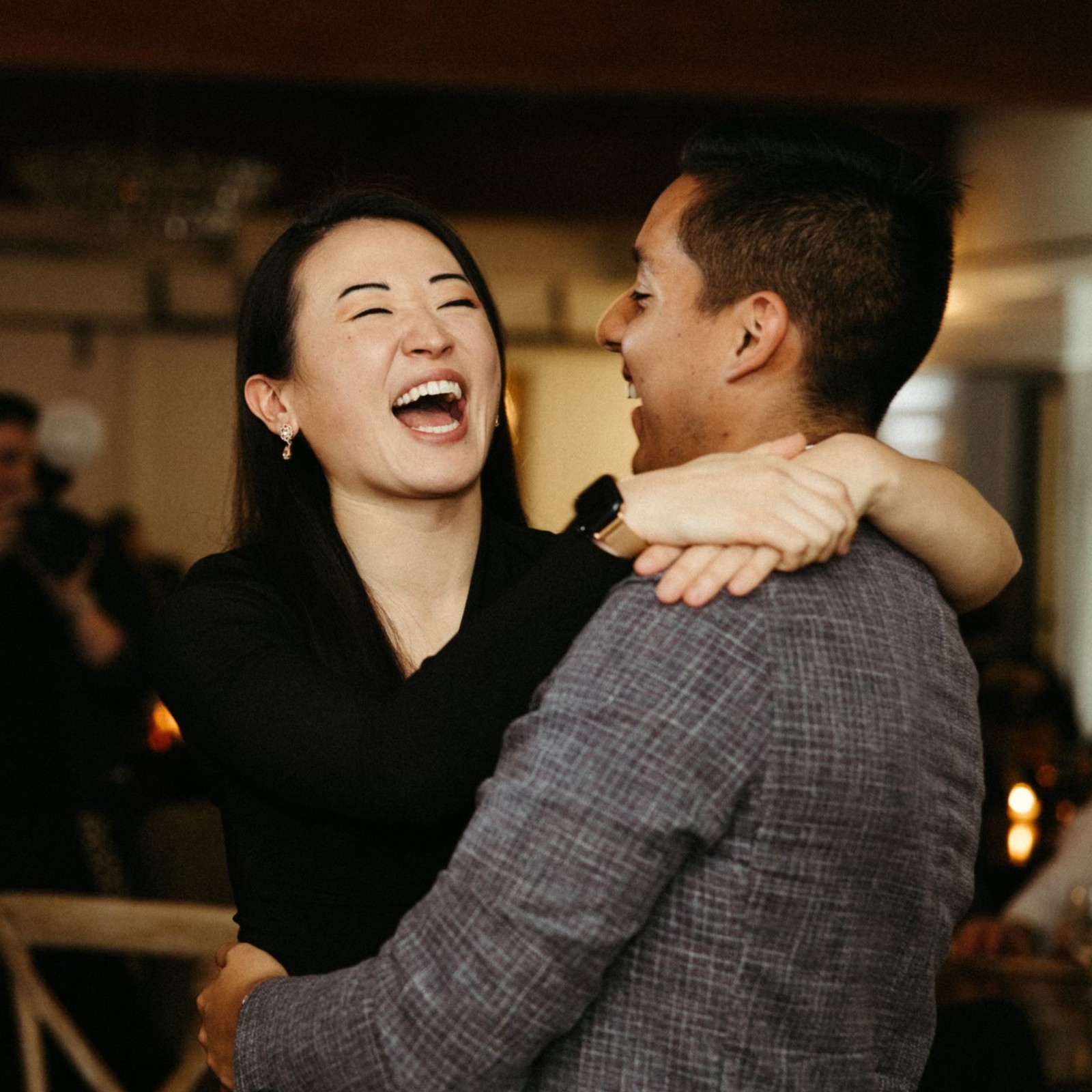 A man and woman laugh as they dance together in a ballroom.