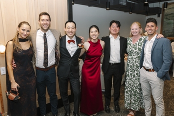 Seven people stand together wearing formal attire.