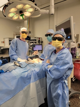 Three people in full surgical gear prepare to begin a case in the operating room.