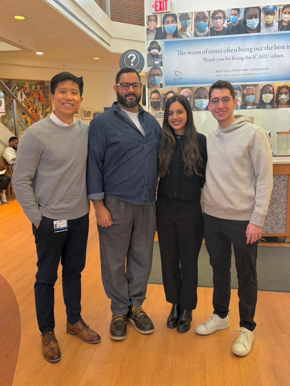 3 men and 1 woman stand together in the atrium of Eastman Dental.